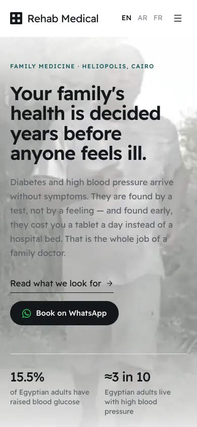 Rehab Medical website on a phone, showing the family medicine headline and a Book on WhatsApp button.